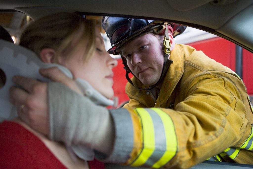 fire fighter rescuing a woman on a car wreck