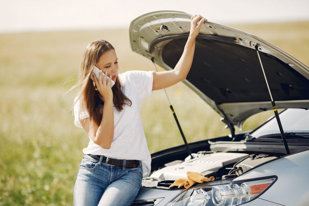 woman using her phone in front of a car